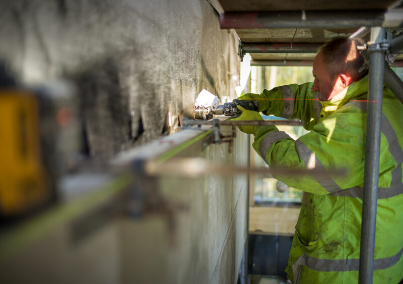 Stonemasons at work hanging stone on timber frame